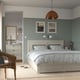 Cosy bedroom with white FÅGELFJÄLLET bed, side lamps, dresser, and wall art. Light green walls, wooden floors, beige rug.