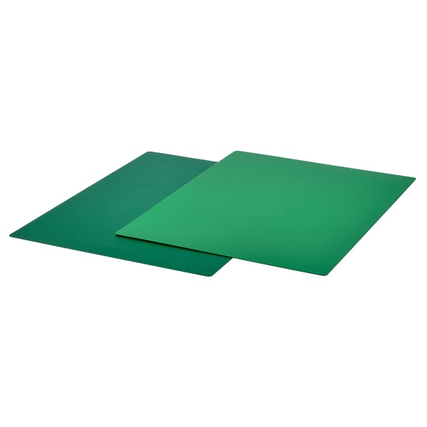 Two green, flexible, square-shaped chopping boards, overlapping, made of thermoplastic elastomer.