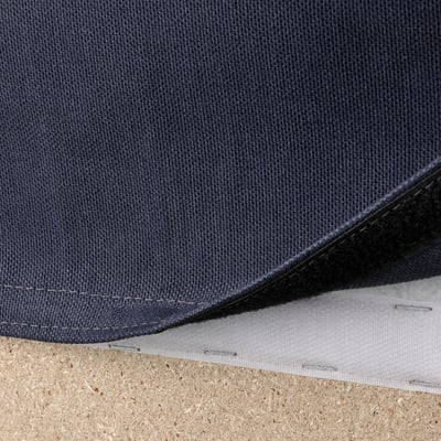 Dark grey fabric with visible stitching and two layers, laid on a textured surface.