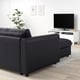 Modern living space with black FINNALA sectional sofa, white tv stand, and green plant. Clean, minimalist design.