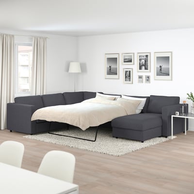 Modern living room with large grey FINNALA sectional sofa, matching bed mattress, white curtains, and wall-art.