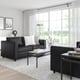 Modern living room with FINNALA sectional sofa, white pillows, coffee table, large windows, and plants.
