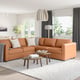 A brown leather l-shaped FINNALA sofa with white accents in a spacious living room, illuminated by a pendant lamp, and featuring a view of greenery.