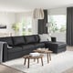 Modern black FINNALA sectional sofa by large window, with chaise lounge and accessories.
