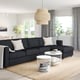 Modern living room with FINNALA grey sectional, white tables, natural rug, hanging lamp, and large windows.
