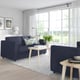 Modern living room: dark blue FINNALA sectional sofa against large windows, light wooden coffee table, white curtains, decorative pillows, and a rug.