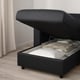 Black upholstered bed with open storage compartment, showing folded linens and pillows inside.