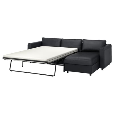 A FINNALA dark grey sofa-bed with a convertible chaise longue. The leather and fabric couch transforms into a comfortable bed with a thick mattress.
