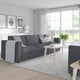Modern grey FINNALA sectional sofa with cushions and coffee table in a bright living room.