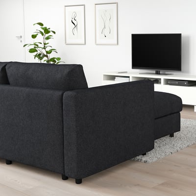 Modern living room with FINNALA black sectional sofa, large tv, plant, art. Sofa is expansive, fits well in spacious room.