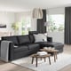 Modern black FINNALA sectional sofa with sleek design, featuring cushions and wooden tables, fits well in spacious room.