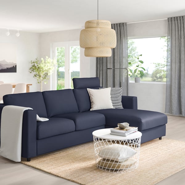 Modern living room with FINNALA dark blue sectional sofa, chaise, white coffee table, lamp, grey curtains, jute rug.