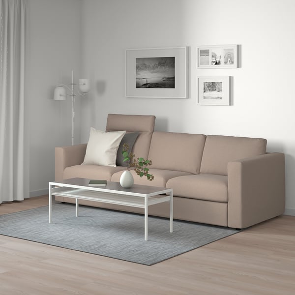 Modern living room with FINNALA sectional sofa in beige, grey rug, white coffee table, and wall art.