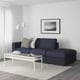 Modern living room: FINNALA dark grey sectional sofa, white coffee table, black & white photo, floor lamp on rug.