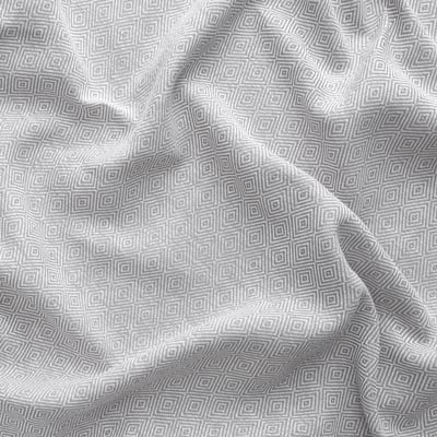 Grey cotton curtains with intricate, repeating geometric patterns, slightly draped, showcasing their textured weave.