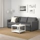 Modern living room with FRIHETEN sofa, coffee table, and rug. Sofa converts to bed, has large storage and colourful pillows.