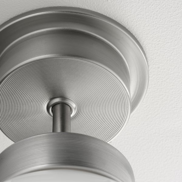 Close-up of a modern ceiling light fixture with sleek, metallic design and glass shade, reflecting light and quality craftsmanship.