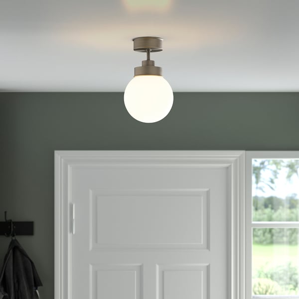 A round glass ceiling light hangs above a white door. The glossy globe diffuses soft, balanced lighting into the space.