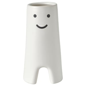 White ceramic vase with smiling face design, cylindrical shape with small cutouts at base.