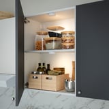 Cabinet with led motion sensor light illuminating organised food containers and storage boxes.