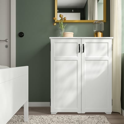 White GREÅKER cabinet with 2 doors, 3 drawers, and countertop decor against green wall.