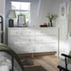 White GULLABERG dresser with 8 drawers, lamp, mirror, flowers. Tall, wide with rustic, traditional style. Wooden knobs. Placed near window.
