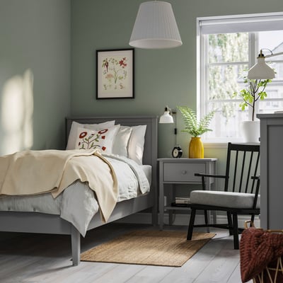 Calm bedroom in sage green with GULLABERG bed, grey accents, white bedding, bedside table, chair, and lamp; cosy, traditional design.