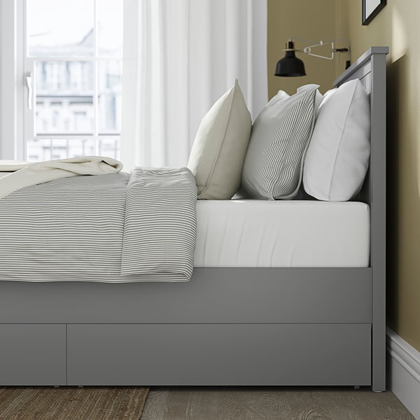 Modern bed with drawers and pillows, offering storage and comfort.