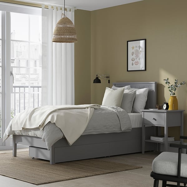 Modern bed setup: GULLABERG grey bed with 2 drawers, white linens, wooden accents, and bedside table. Balcony view outside.