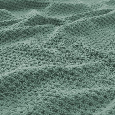 Close-up of soft, fluffy green towel with intricate weave pattern, showcasing its texture and quality.
