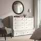 White HAUGA chest in bedroom with eight drawers, mirror, chair, and lamp.