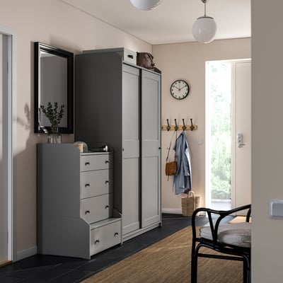 Modern entryway with HAUGA wardrobe, chest, hooks, clock, chair, and pendant light.