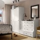 Cosy bedroom with HAUGA wardrobe and dresser. Sliding doors, patterned bed, lamp, and flowers. Soft light from window and ceiling.