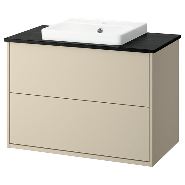 A beige HAVBÄCK bathroom vanity with a black countertop and a built-in white sink. The clean design two drawers.