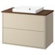 A beige HAVBÄCK bathroom vanity with a wooden countertop and a white ceramic sink. It has two drawers for storage.