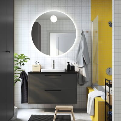 Modern bathroom with HAVBÄCK vanity, mirror, shower, plant, and towels.