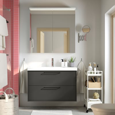 Modern bathroom with grey HAVBÄCK vanity, double drawers, sink, mirror cabinet, towel rack, and shelving unit with toiletries and towels.