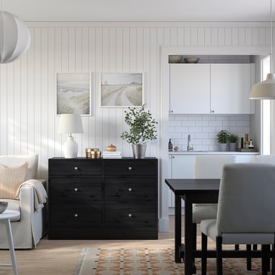 Modern living room with black HAVSTA drawers, grey sofa, and kitchen area.