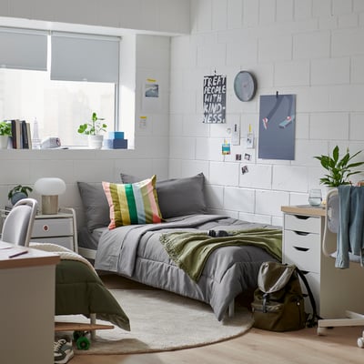 Small cosy room with a HEDFRYLE grey comforter set on twin bed, colourful pillows, plants, and wall art.