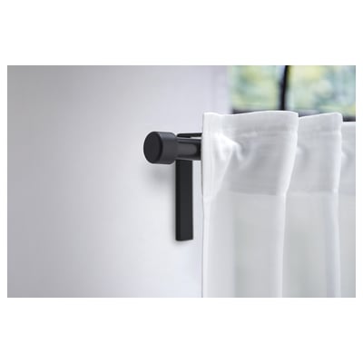 Black curtain finial, minimalist design, round shape, mounted on wall, holds white curtain.