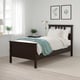 Black HEMNES bed with white bedding, blue blanket, plants above, tall curtains.