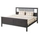 A stylish black HEMNES bed with beige chequered bedding and pillows, made of solid wood.