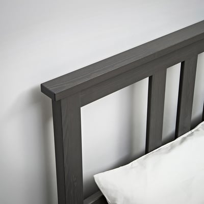 Dark wood bed frame with clean lines and a white pillow.