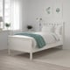 HEMNES white bed, teal blanket, wood floor, modern decor, small plants, wall art, light hues, minimalist design.