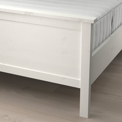 A white bed with adjustable slats, supporting a quilted white mattress, designed for comfort and durability.