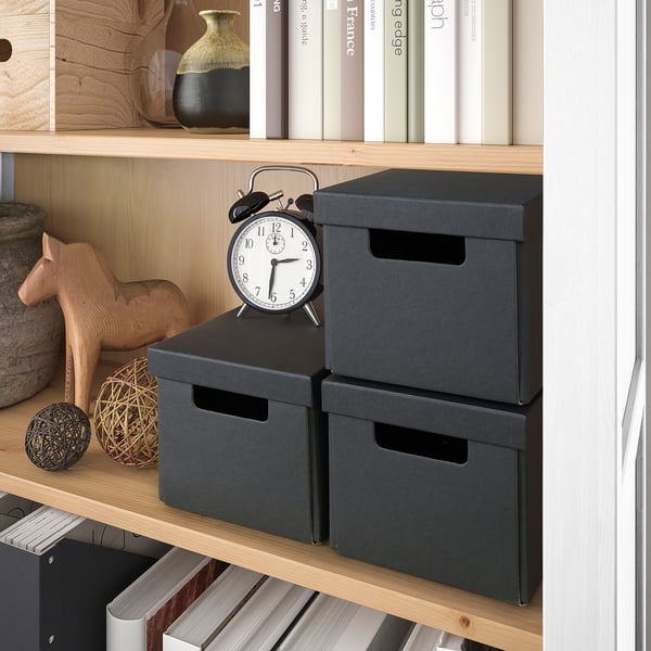 Shelf with boxes, clock, and decor. Holds items neatly.