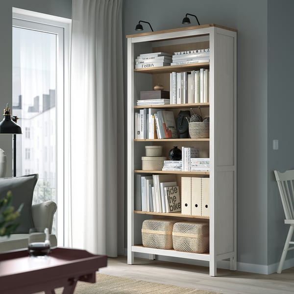 White HEMNES bookcase with books and decor, tall, solid wood, fits cosy room.