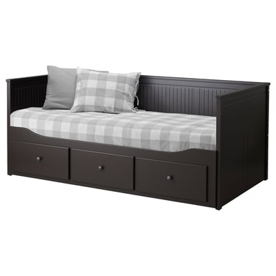 The HEMNES black wooden day-bed has grey and white checked bedding, providing both comfort and storage.