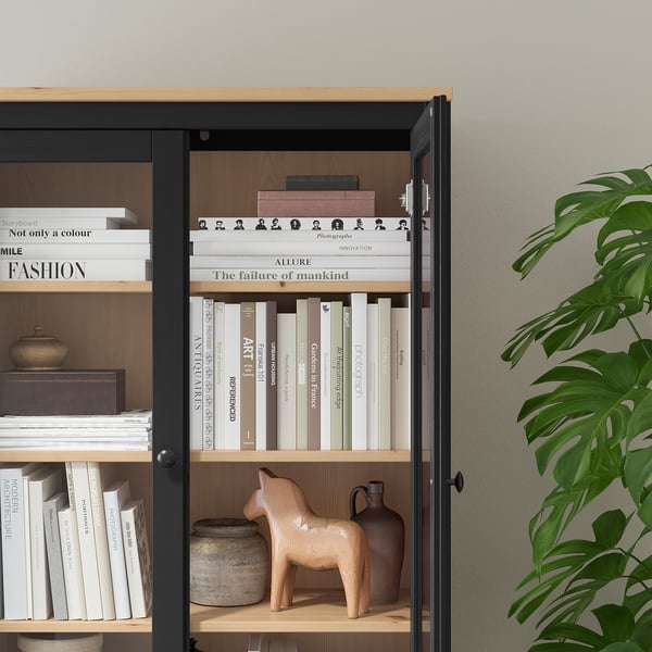 Bookshelf with glass doors, wooden shelves, adjustable shelves, and decorative items.