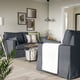 Modern living room with grey HYLTARP sofa, cushions, coffee table, hanging lamp, art frames, and plant.